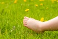 Child bare feet resting on a sunny green meadow with bright yell