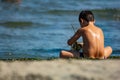 Child from behind sitting on the beach by the sea playing, photo taken at Sottomarina Chioggia.