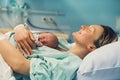 Child birth in maternity hospital. Mother and newborn. Young mom hugging her newborn baby after delivery. Woman giving birth