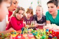 Child on birthday party blowing candles on cake