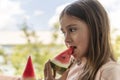 The child bites off a piece of ripe red juicy watermelon. cute little girl eating water-melon in summertime Royalty Free Stock Photo