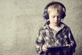 Child blond Boy listening to music or watching movie with headphones and using digital table Royalty Free Stock Photo