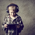 Child blond Boy listening to music or watching movie with headphones and using digital table Royalty Free Stock Photo