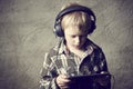 Child blond Boy listening to music or watching movie with headphones and using digital table Royalty Free Stock Photo