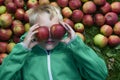 Child blond boy lying on the green grass background with apples glasses