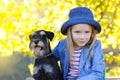 Child blond girl lovingly embraces his pet schnauzer dog. Friendship. Autumn colors.