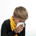 A child blows his nose into a napkin, children's seasonal diseases, a boy wrapped in a scarf. Royalty Free Stock Photo