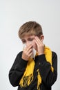 A child blows his nose into a napkin, children's seasonal diseases, a boy wrapped in a scarf. Royalty Free Stock Photo