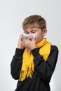 A child blows his nose into a napkin, children's seasonal diseases, a boy wrapped in a scarf. Royalty Free Stock Photo