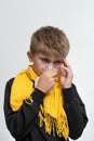 A child blows his nose into a napkin, children's seasonal diseases, a boy wrapped in a scarf. Royalty Free Stock Photo