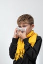 A child blows his nose into a napkin, children's seasonal diseases, a boy wrapped in a scarf. Royalty Free Stock Photo