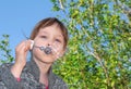 A child blows a soap bubble in the open air. A girl plays with soap bubbles