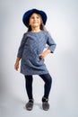 A child in a blue dress with white and black spots, a blue hat, blue tights and gray shoes isolated on a white background. Royalty Free Stock Photo