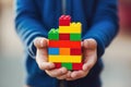 Child in blue presenting a colorful tower of interlocking building blocks, symbolizing creativity and structured play Royalty Free Stock Photo