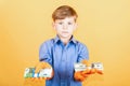 A child in a blue shirt and washing gloves is holding a pack of dollars in one hand and a pack of euro notes in the other. The Royalty Free Stock Photo