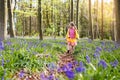 Child with bluebell flowers in spring forest