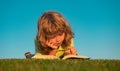 Child boy with a book in the garden. Kid is readding a book playing outdoors in summer day. Kids imagination, innovation