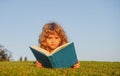 Child boy with a book in the garden. Kids success, successful leader concept. Kid is readding a book playing outdoors in Royalty Free Stock Photo