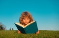 Child boy with a book in the garden. Kids success, successful leader concept. Kid is readding a book playing outdoors in Royalty Free Stock Photo