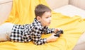 The child boy in checked shirt lying on the couch with black joystick in his hands playing the video game. Playing video Royalty Free Stock Photo