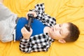 The child boy in checked shirt lying on the couch with black joystick in his hands playing the video game. Playing video Royalty Free Stock Photo