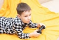 The child boy in checked shirt lying on the couch with black joystick in his hands playing the video game. Playing video Royalty Free Stock Photo