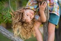 Child boy climbing high tree in the summer park. Portrait of cute kid boy sitting on the tree, climbing a tree. Active Royalty Free Stock Photo