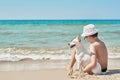 Child boy with dog jack russel on beach. Best friends rest on vacation, play in sand against sea. Tourism and vacation on ocean. Royalty Free Stock Photo