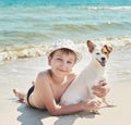 Child boy with dog jack russel on beach. Best friends rest on vacation, play in sand against sea. Tourism and vacation on ocean. Royalty Free Stock Photo