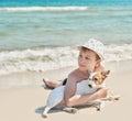 Child boy with dog jack russel on beach. Best friends rest on vacation, play in sand against sea. Tourism and vacation on ocean. Royalty Free Stock Photo