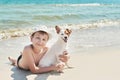 Child boy with dog jack russel on beach. Best friends rest on vacation, play in sand against sea. Tourism and vacation on ocean. Royalty Free Stock Photo