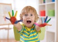 Child boy draws with hands and shows multi-colored painted palms. Children`s educational games with paints. Royalty Free Stock Photo