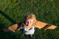 Child boy dreams and travels on green grass in park. Boy with airplane toy outdoors. Happy child playing with toy