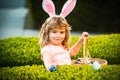 Child boy with easter eggs and bunny ears laying on grass. Child gathering eggs, easter egg hunt concept. Royalty Free Stock Photo
