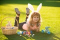 Child boy with easter eggs and bunny ears painting eggs outdoor. Cute kid having happy easter in park. Royalty Free Stock Photo