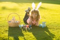 Child boy with easter eggs and bunny ears painting eggs outdoor. Cute kid having happy easter in park. Royalty Free Stock Photo