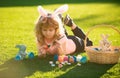 Child boy with easter eggs and bunny ears painting eggs outdoor. Cute kid having happy easter in park. Royalty Free Stock Photo