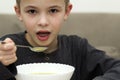 Child boy eating soup from a plate with a spoon Royalty Free Stock Photo