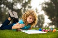 Child boy enjoying art and craft drawing in backyard or spring park. Children drawing draw with pencils outdoor. Happy