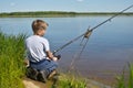 Boy child fisherman sits on shore and looks at float. Fishing with children Royalty Free Stock Photo