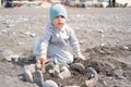 Child boy folds castle of stones, play with rocks on the shore on a sunny day.