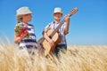 Child boy and girl with guitar are in the yellow wheat field, bright sun, summer landscape Royalty Free Stock Photo