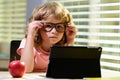 Child boy in glasses using a tablet and study online with video call teacher at home, homeschooling, distant learning E Royalty Free Stock Photo