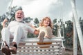 Child boy and grandfather swinging in summer garden. Grand dad and grandson sitting on swing in park. Generations ages. Royalty Free Stock Photo