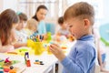 Child boy and group of kids working with colorful clay toy at nursery or kindergarten Royalty Free Stock Photo