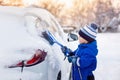 child boy helping to brush snow from fathers car