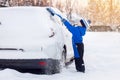 child boy helping to brush snow from parents car