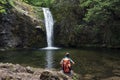 Child boy with hiking backpack sitting alone in forest near lake and watching waterfall. Children`s adventure learning Royalty Free Stock Photo