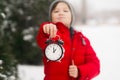 A child boy holds a clock alarm clock in his hands.Winter d Royalty Free Stock Photo