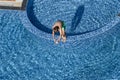 Child boy jumping into blue water of resort hotel swimming pool. Summer vacation, kids sports and fun. View from above Royalty Free Stock Photo